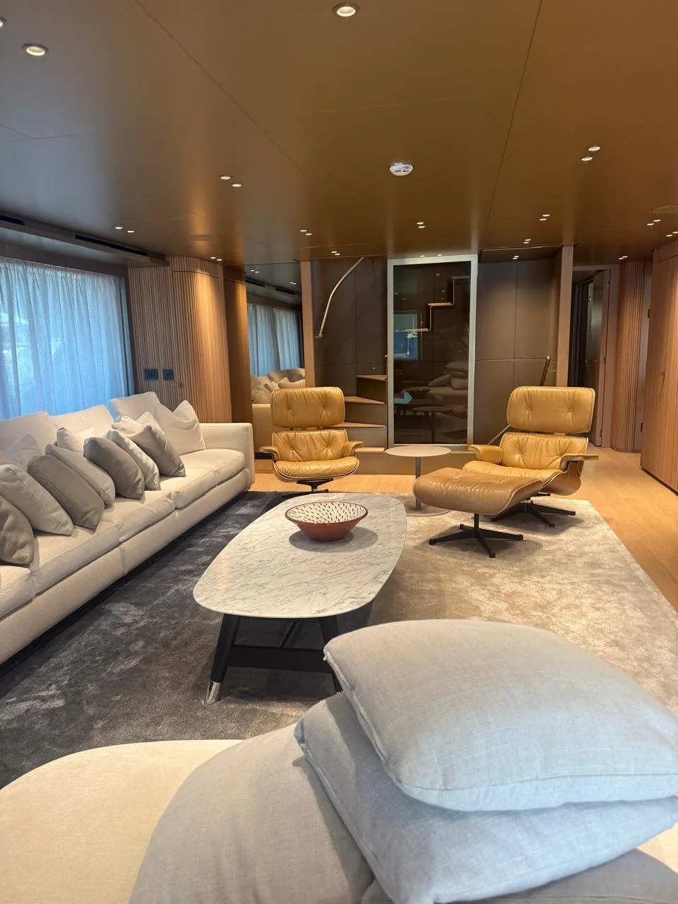Main deck salon of EOS with two Eames lounge chairs and a Carrara marble coffee table